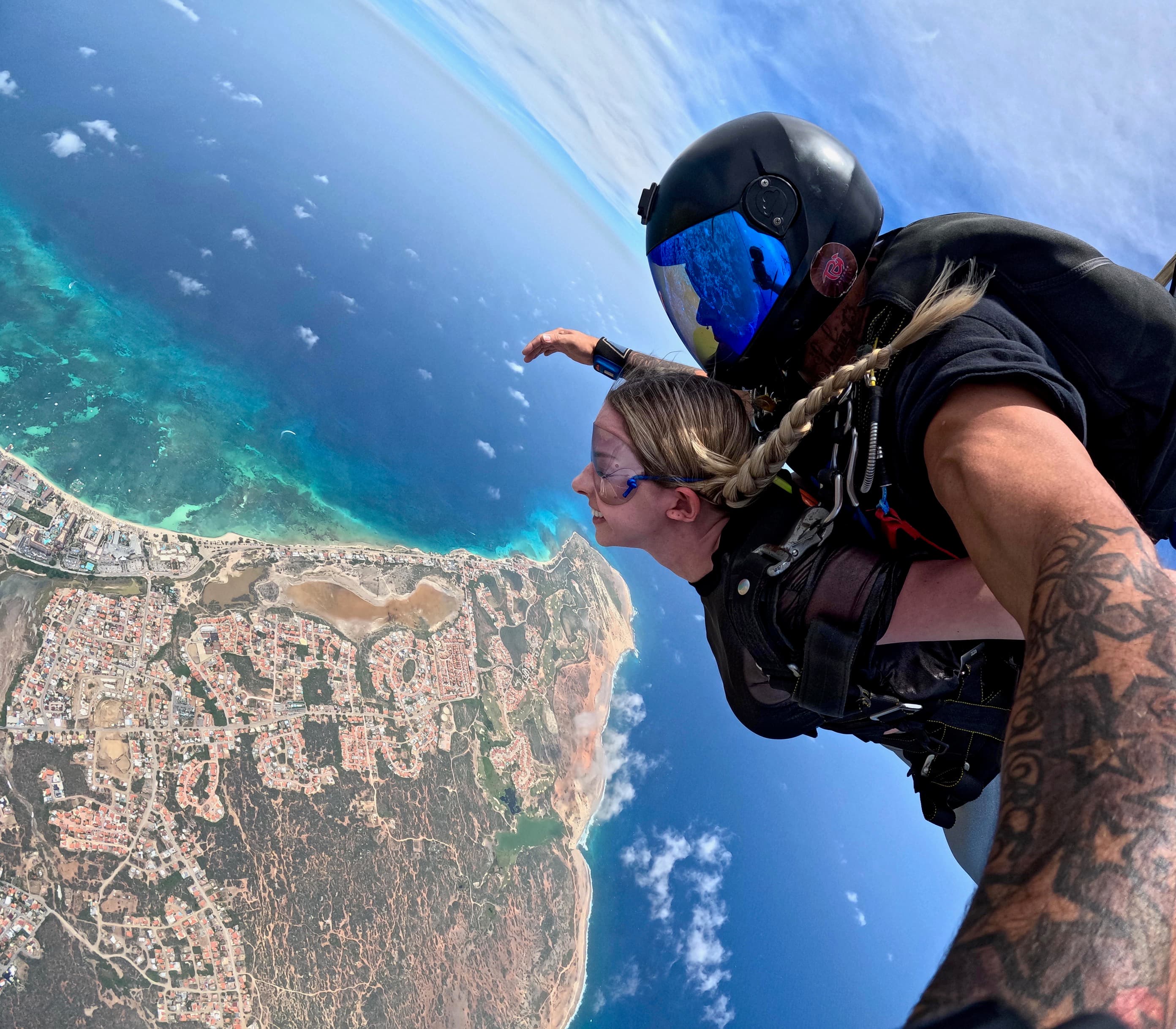 Travel advisor sky diving over a peninsula.