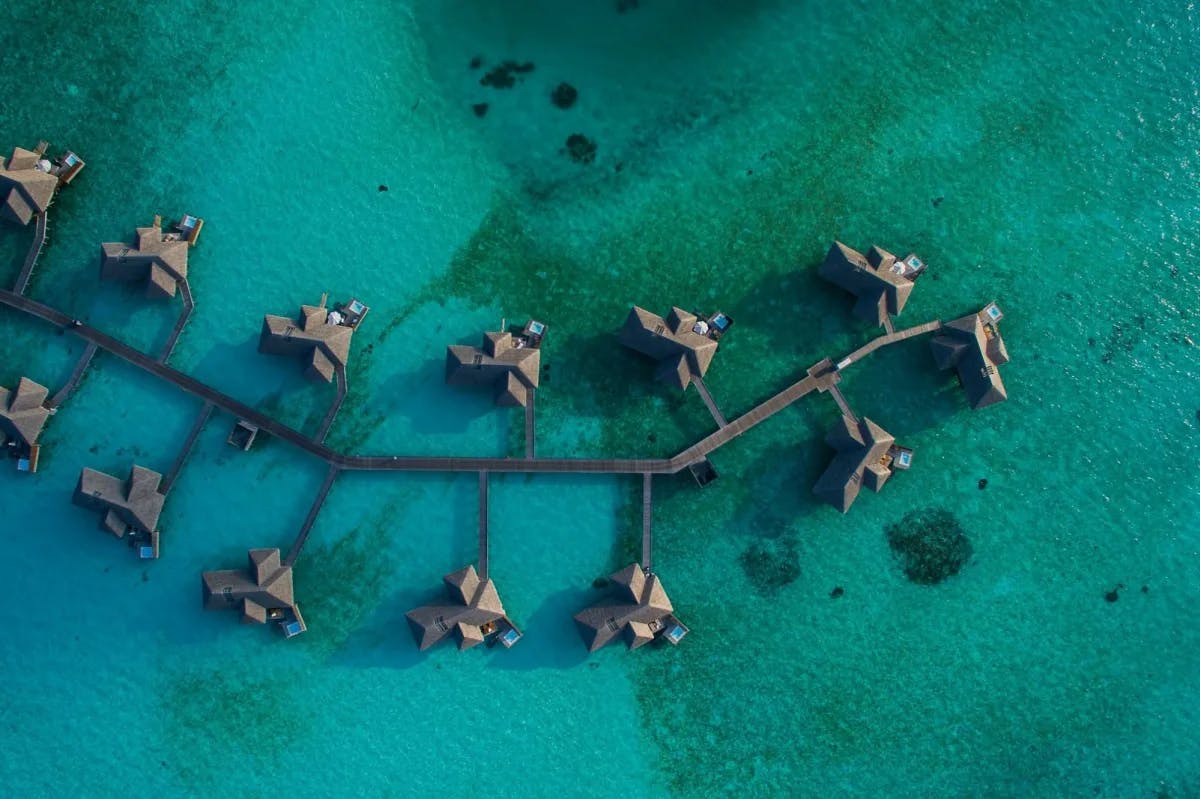 A pier connects a dozen overwater bungalows just off the shoreline somewhere in the Maldives