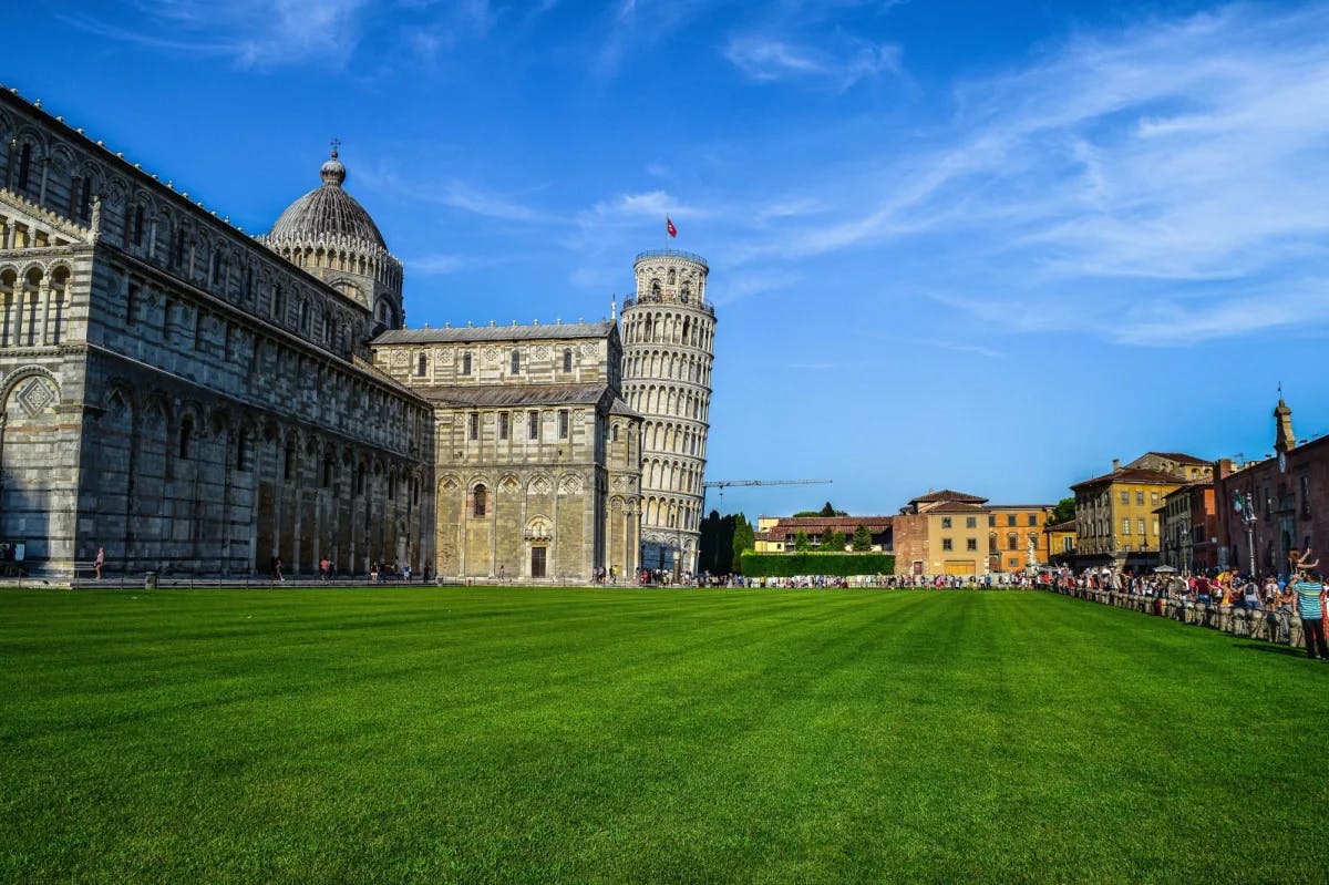 Buildings and leaning tower under blue sky.