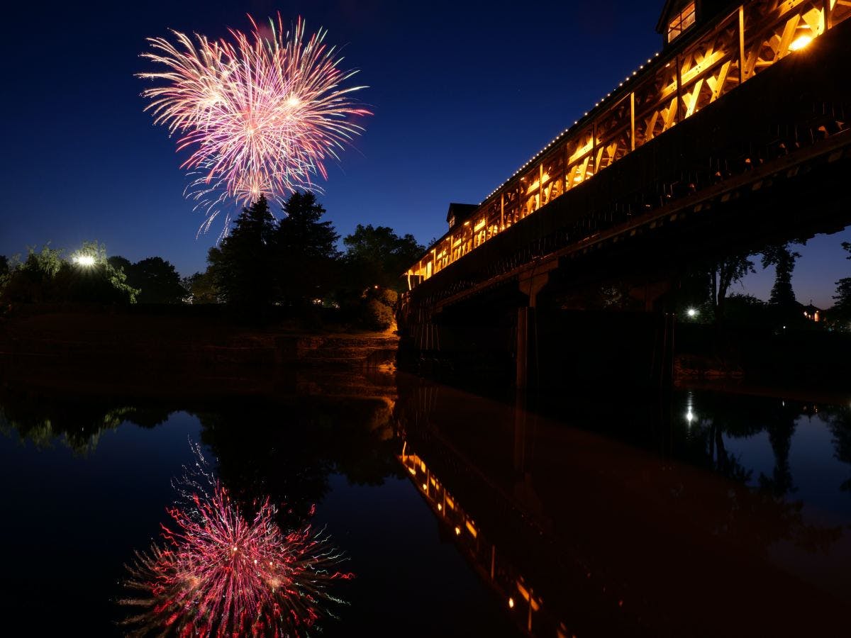 an ariel view of a bridge over water with fireworks in the night sky