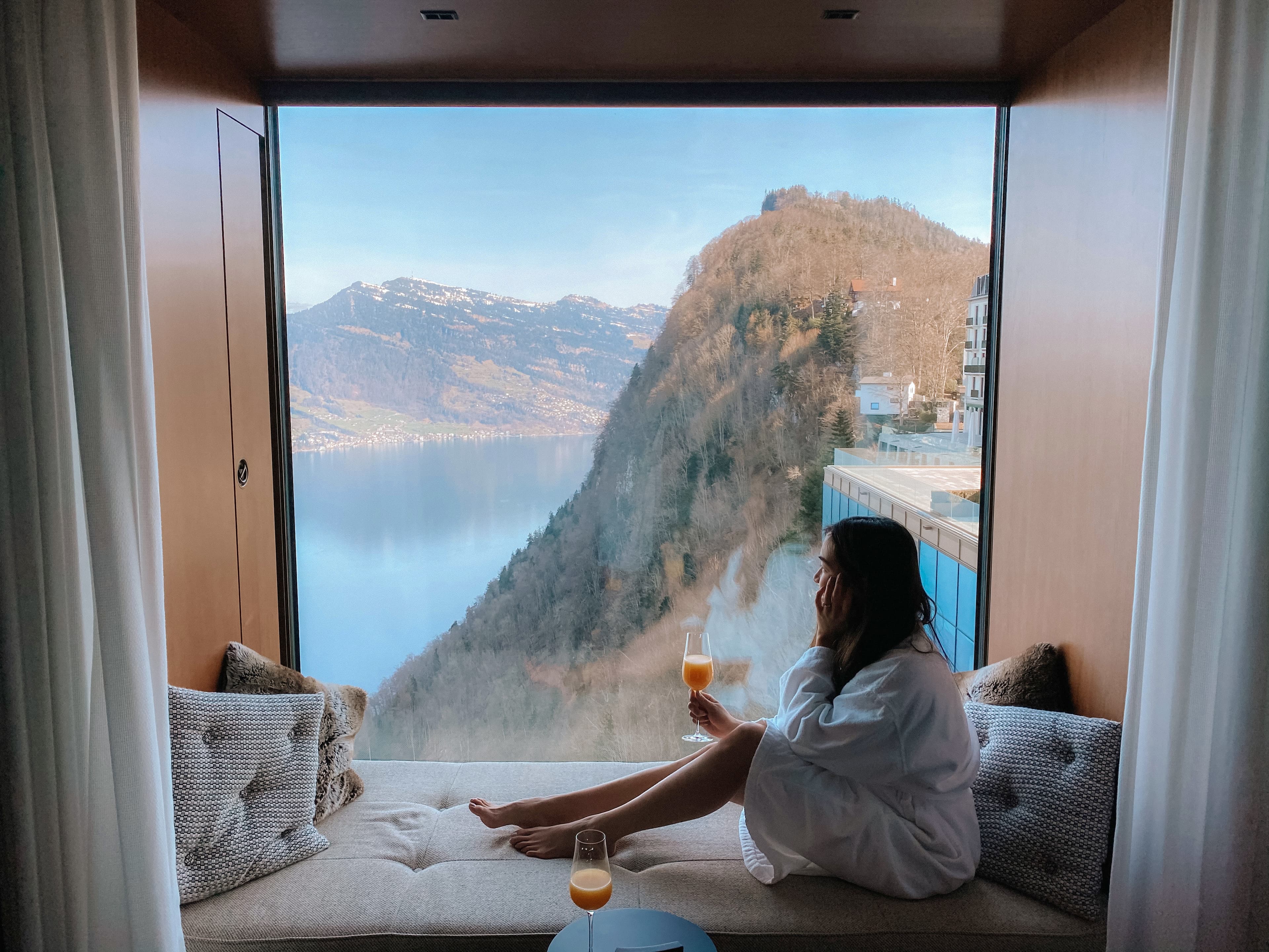 Travel advisor sitting in a window nook overlooking a mountain lake.