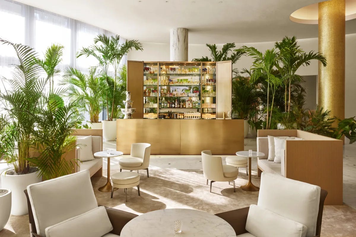 a chic lobby area with a gold bar, plush white furniture, and green tropical plants