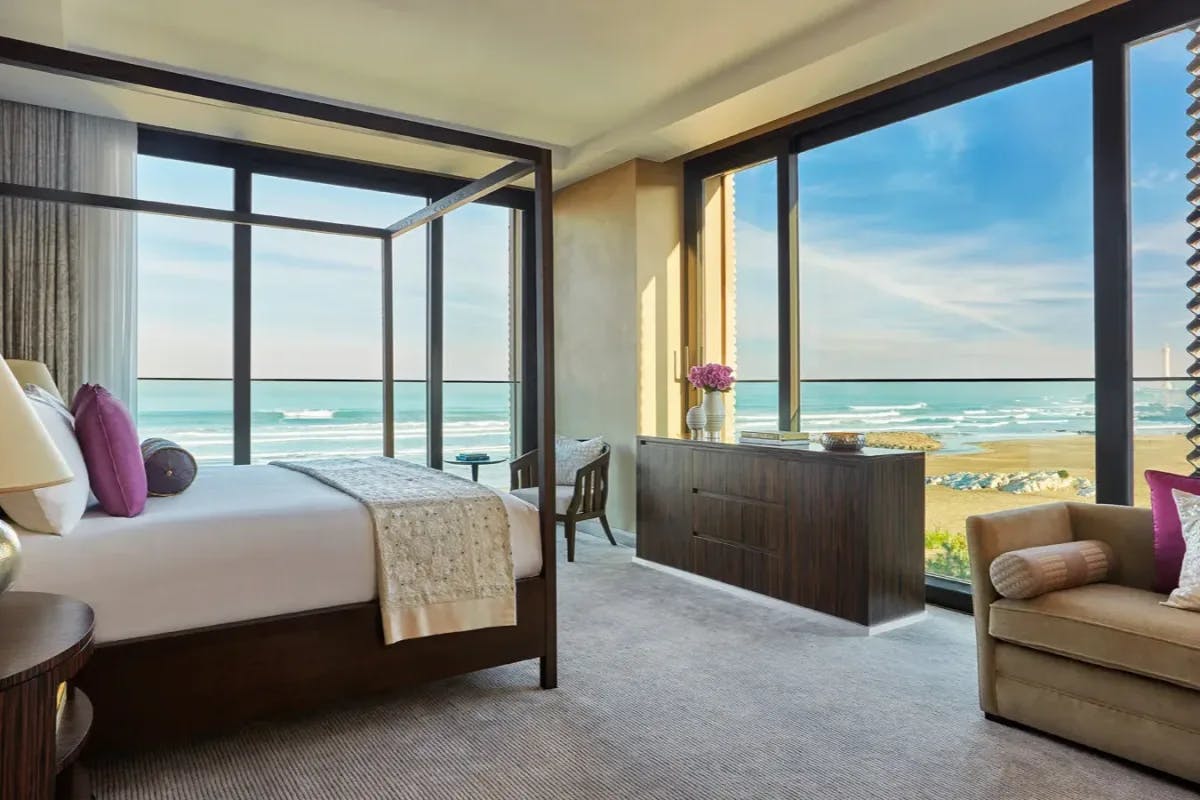 A well kept suite with simple, if elegant furniture features floor-to-ceiling windows that overlook the Casablanca shoreline in front of the hotel