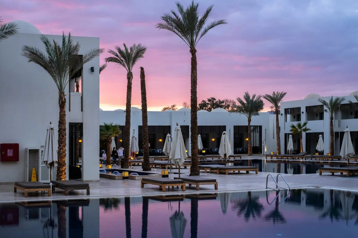 Pinks, purples and blues fill a twilight sky over a ritzy Egyptian beach resort filled with pools, lavish furnishings and palm trees