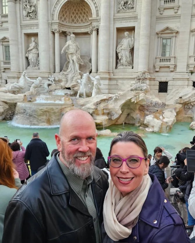 Susan posing in front of the Trevi fountain with her partner surrounded by tourists