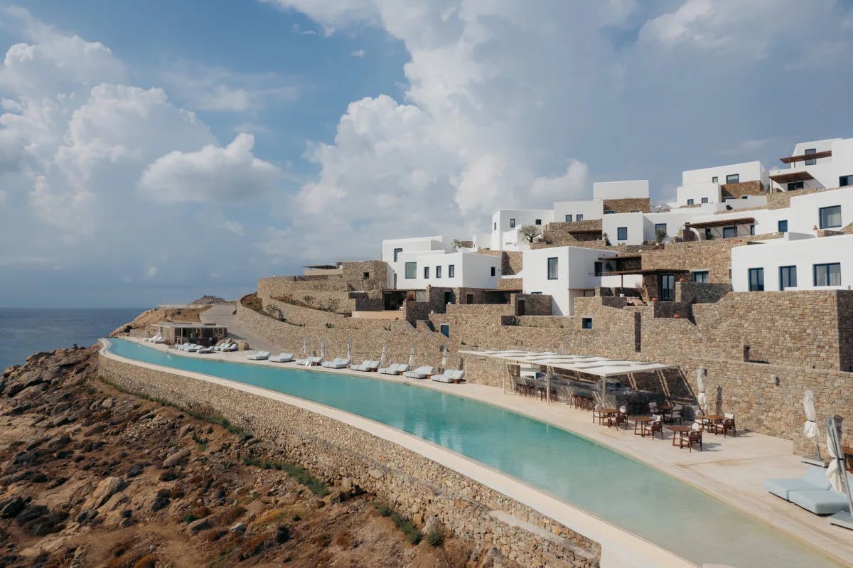 a collection of white square structures on a cliffside overlooking an infinity pool