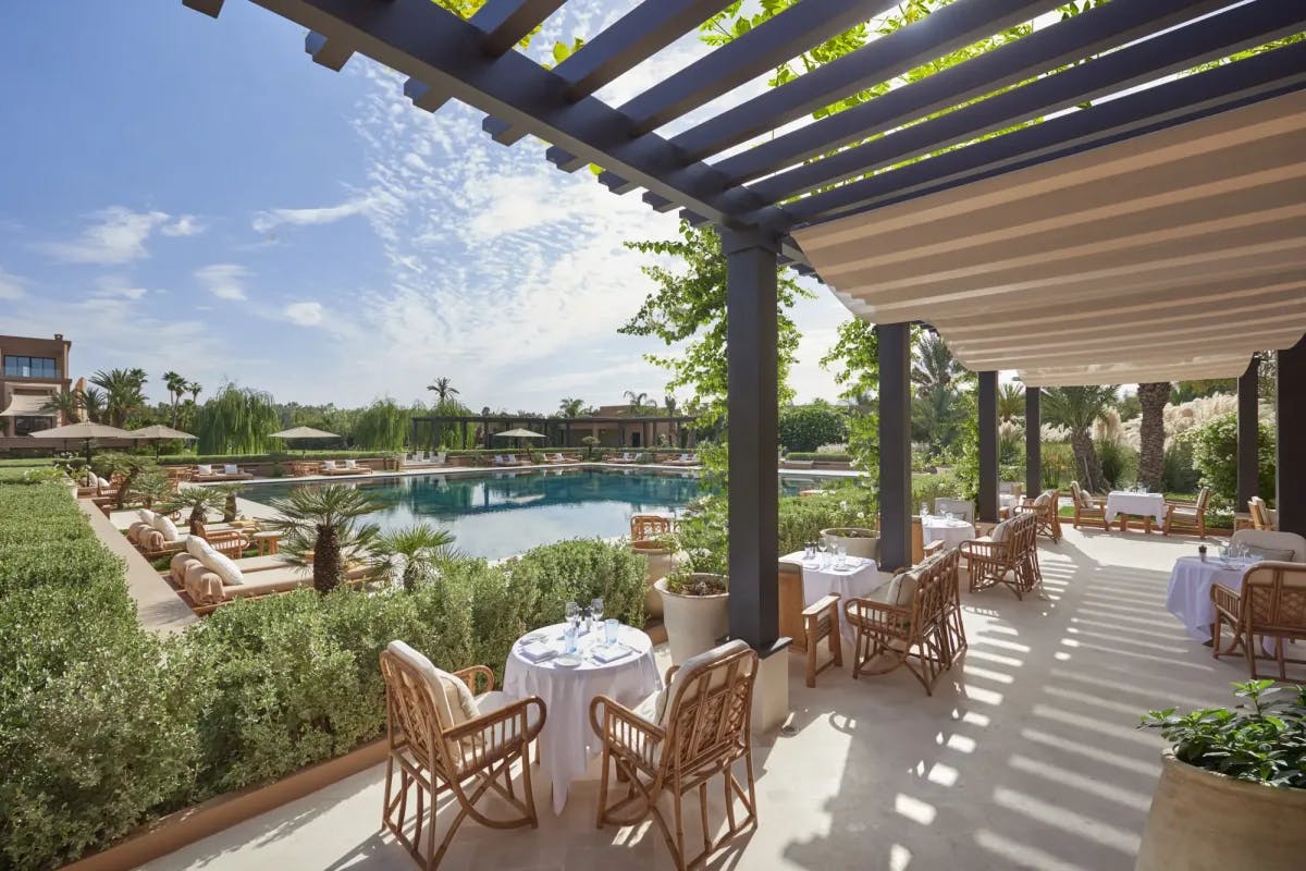 Grounds at Mandarin Oriental, Marrakech: fancy outdoor seating beneath a pergola, loungers surrounding a sapphire-blue pool, gardens and hedges separating the spaces