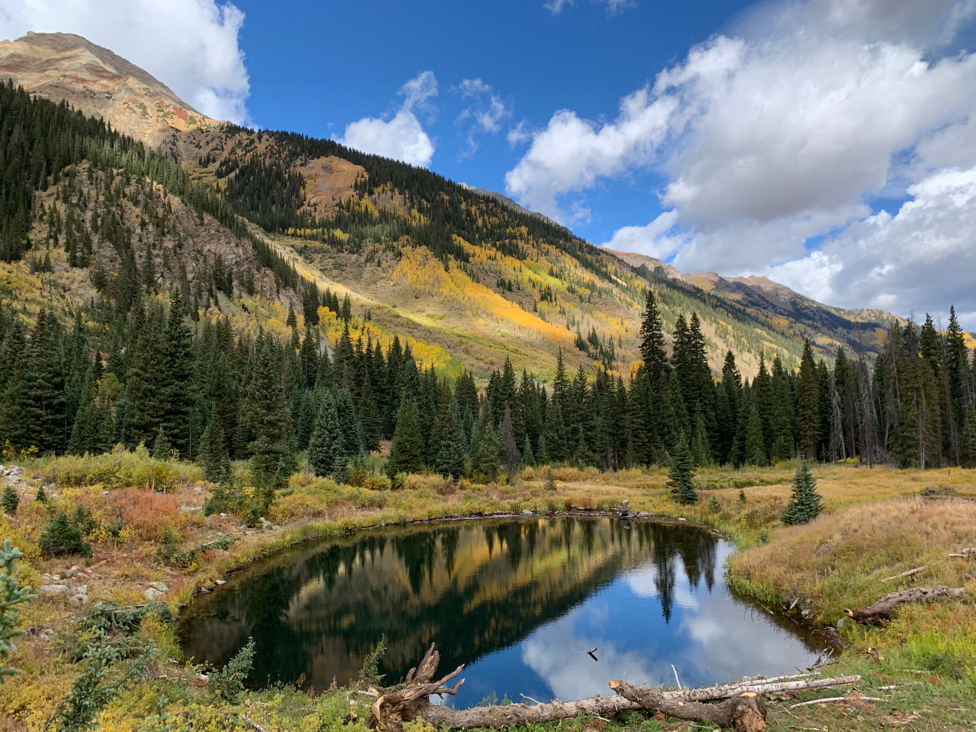 green mountain region with a small pool reflecting blue sky