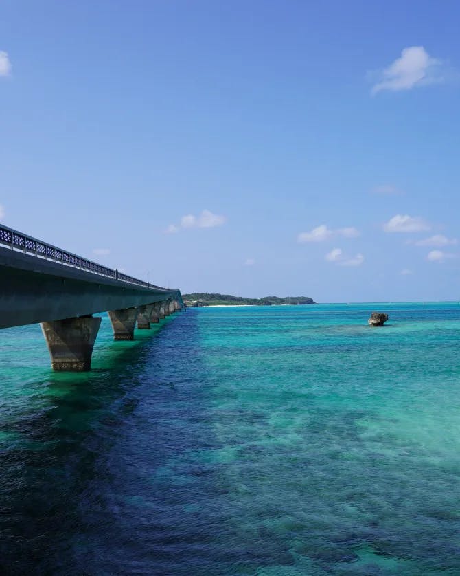 A body of turquoise water under a long bridge 