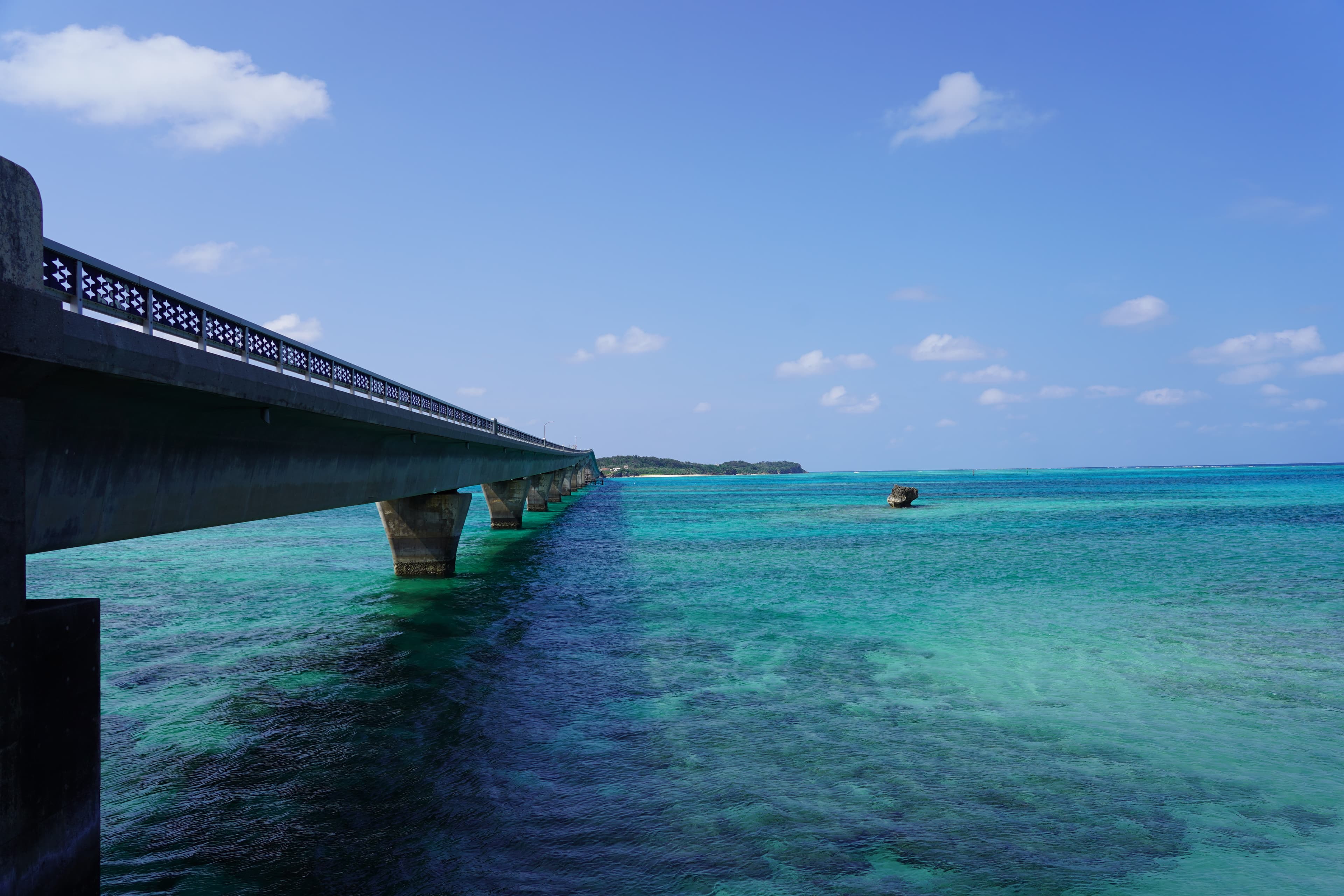 A body of turquoise water under a long bridge