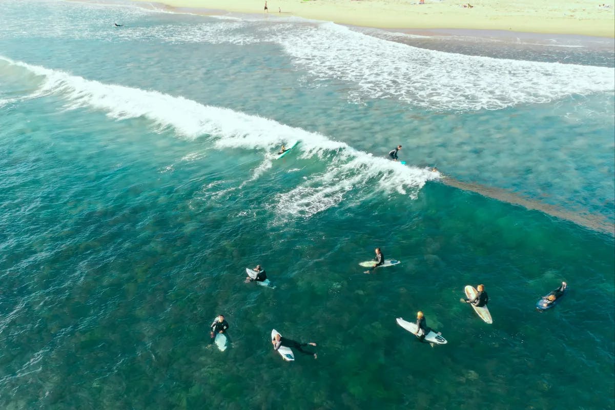 A picture of people surfing on the beach during the daytime.