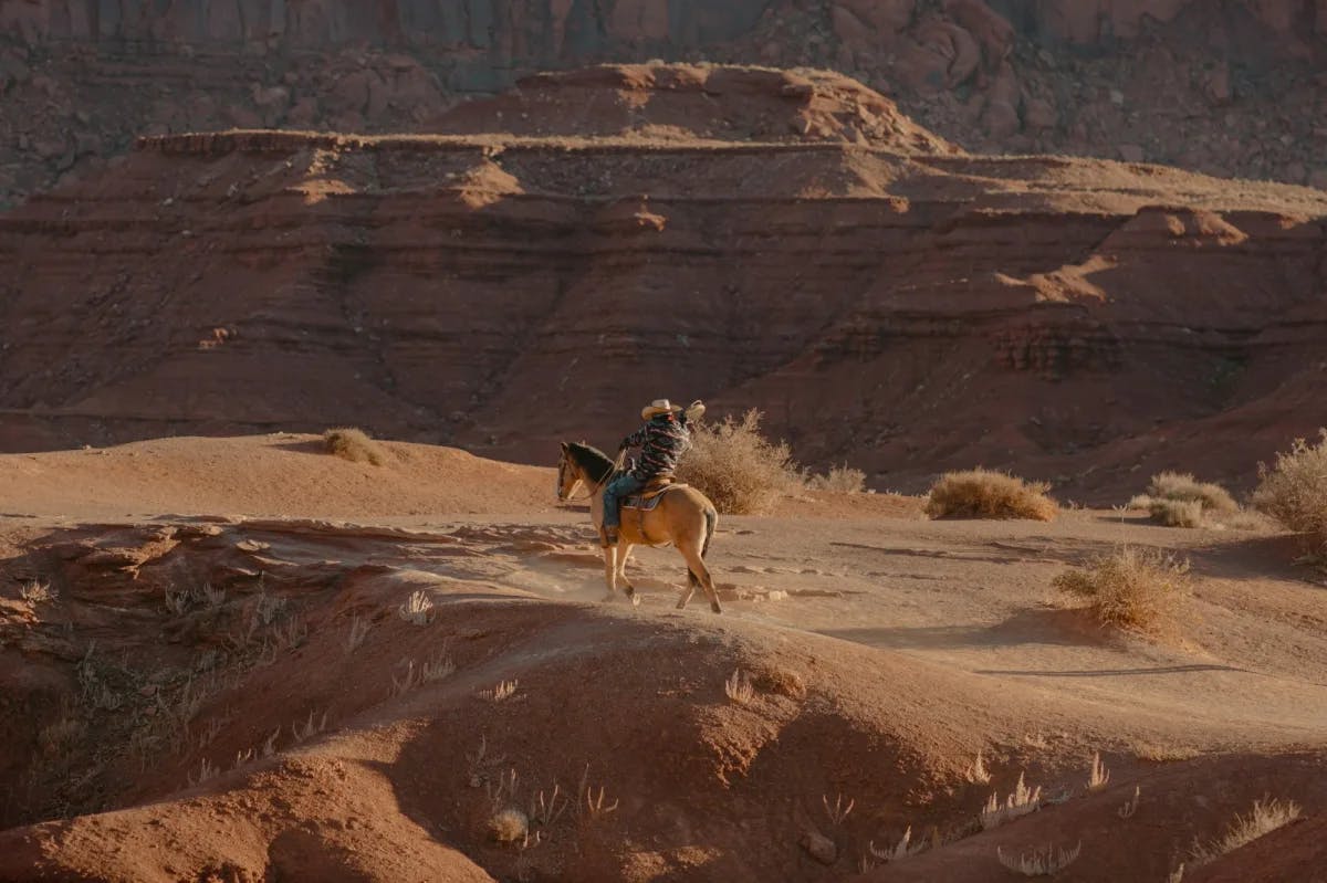 A lone rider treks through the desert of Monument Valley, AZ on horseback