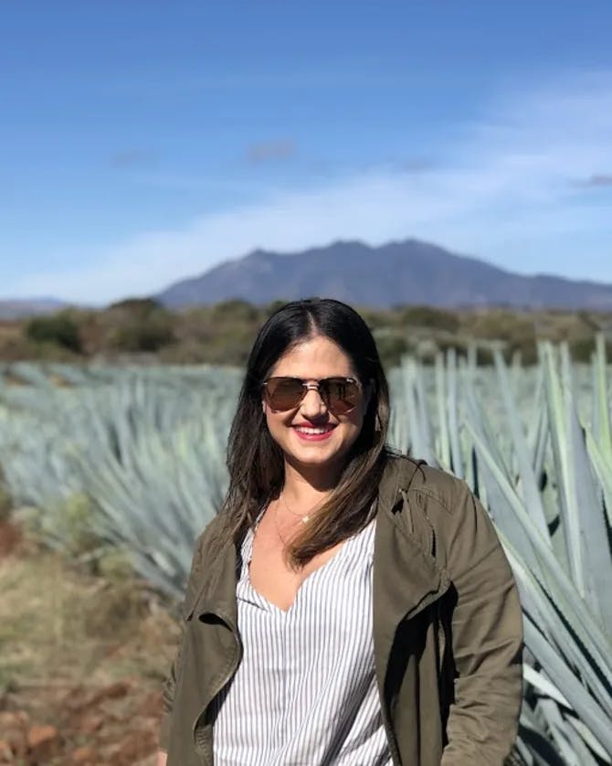 Picture of Mariela standing in front of aloe pants with a mountain in the background