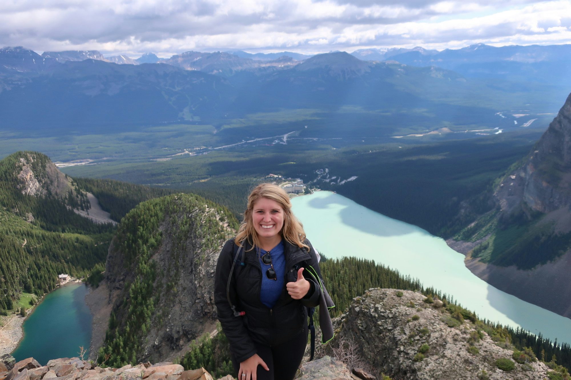 Travel advisor Kirsten Johansson stands on top of a mountain overlooking a scenic lake.