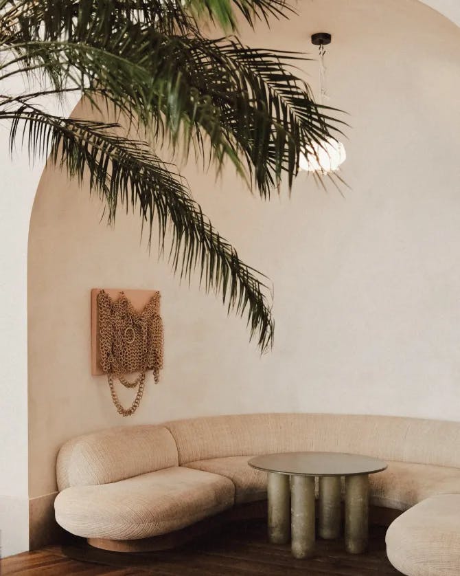 A white sofa next to a decorative table and palm tree