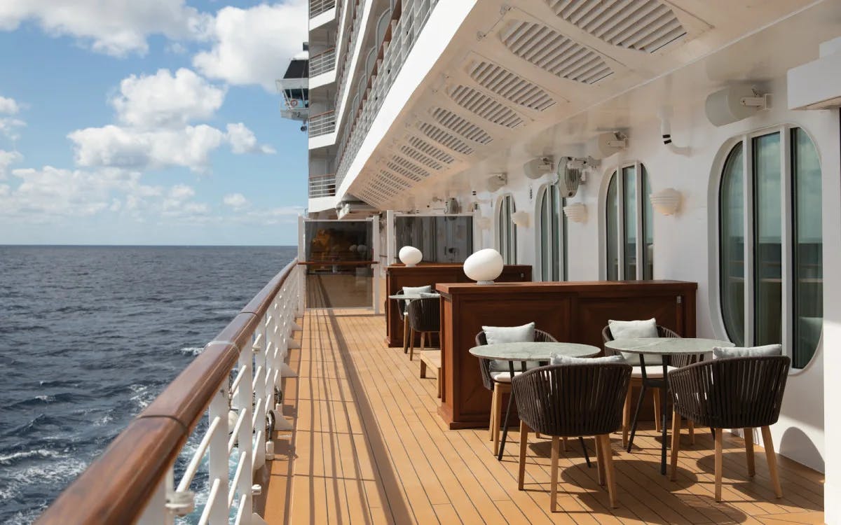 tables and chairs on a cruise balcony overlooking the ocean
