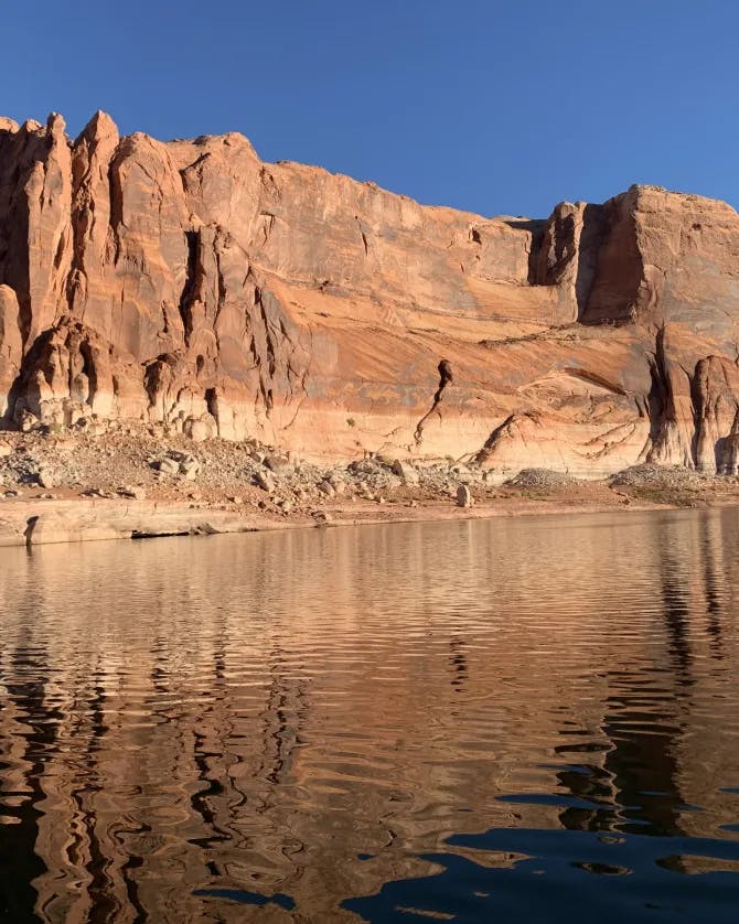 A picture of Lake Powell on a sunny day with rocks in the background.