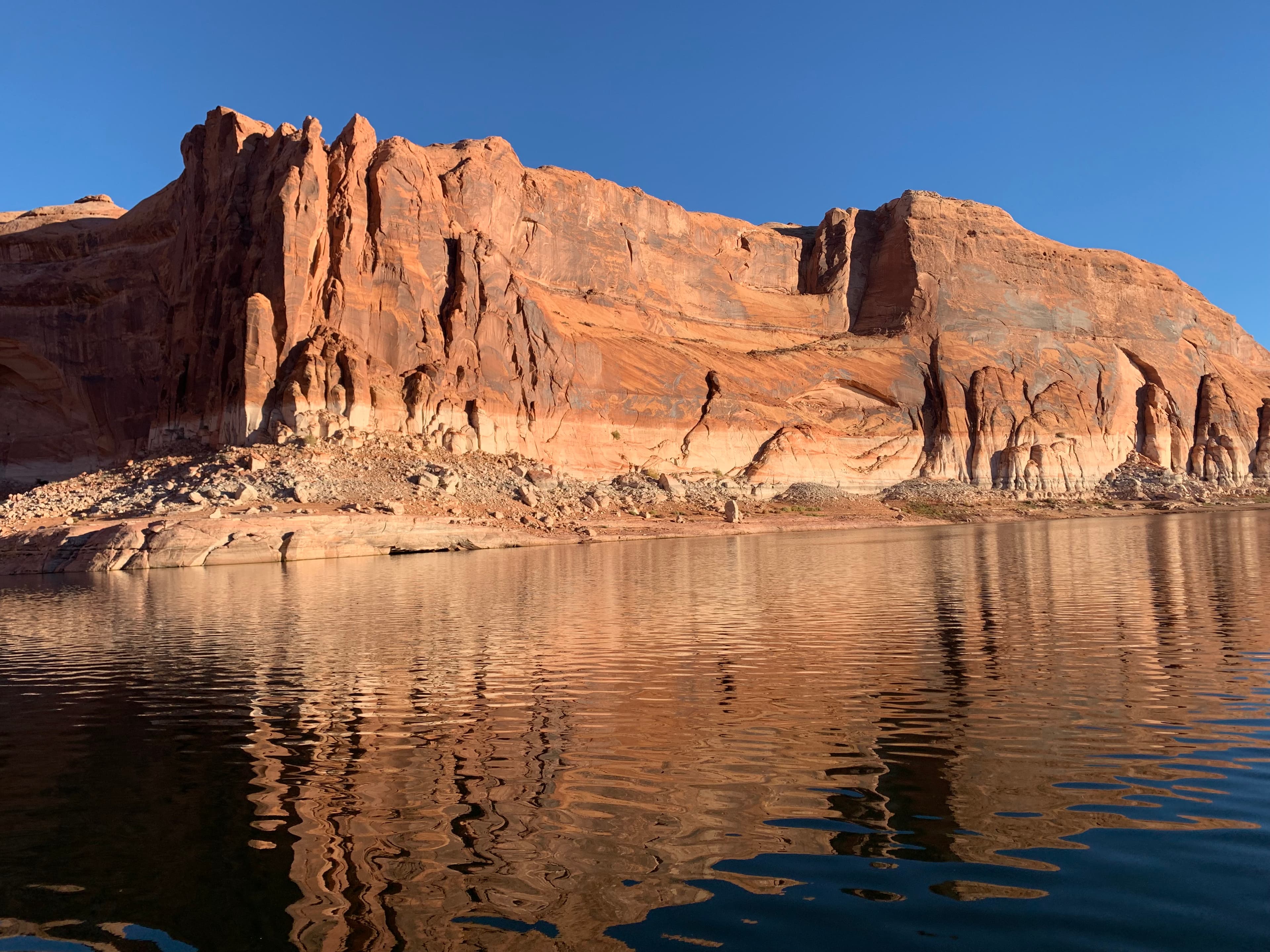 A picture of Lake Powell on a sunny day with rocks in the background.