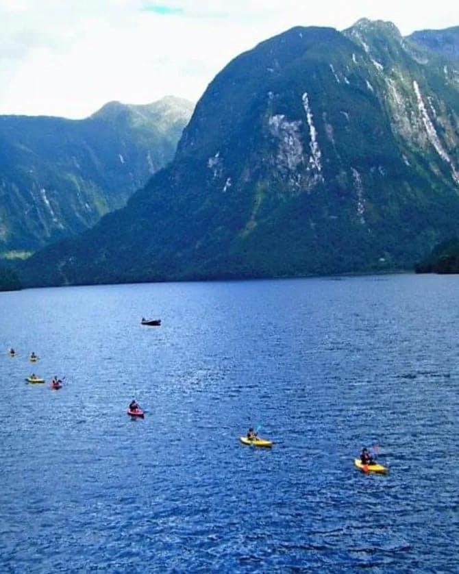 A lake with kayakers surrounded by mountains