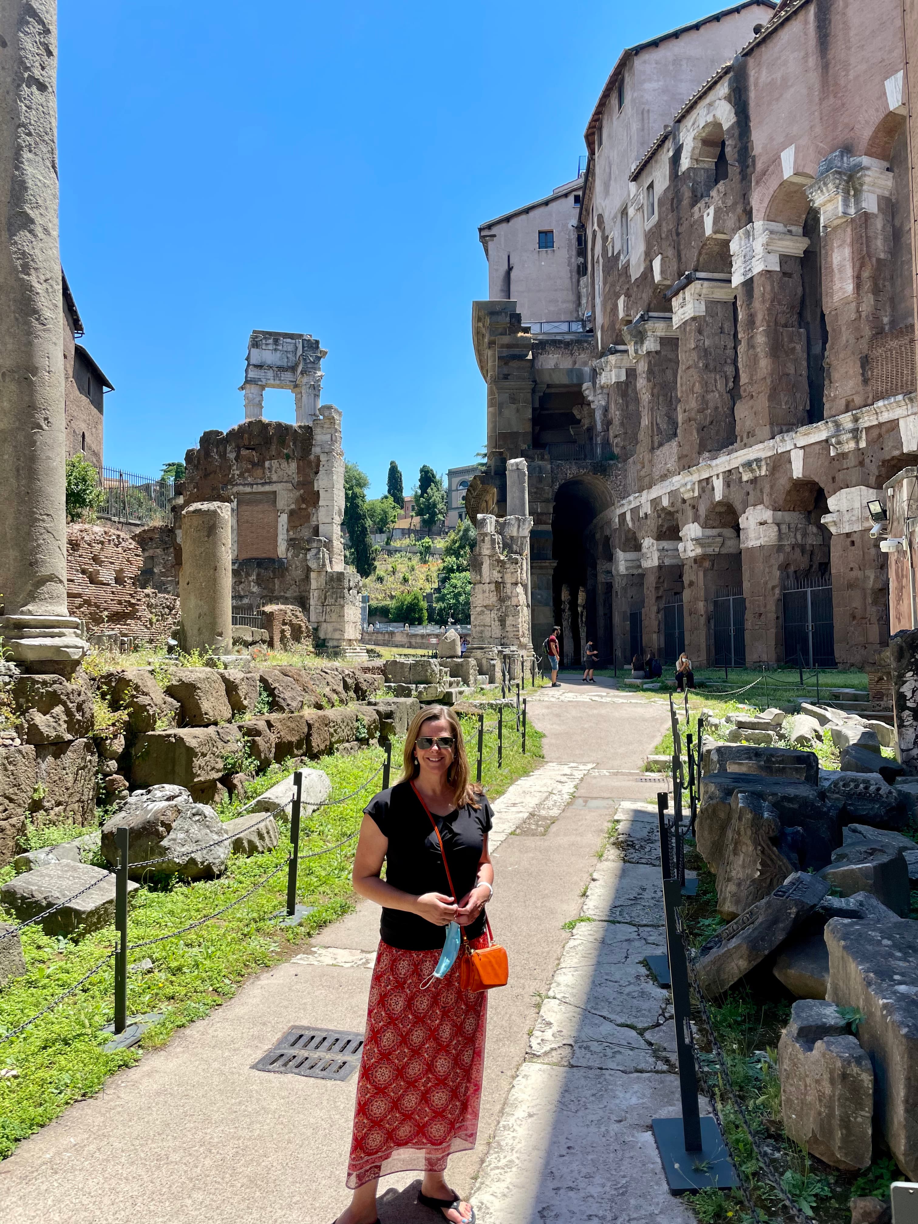 Jennifer wearing a black top and red skirt while standing in front of the Marcellus Theater on a sunny day