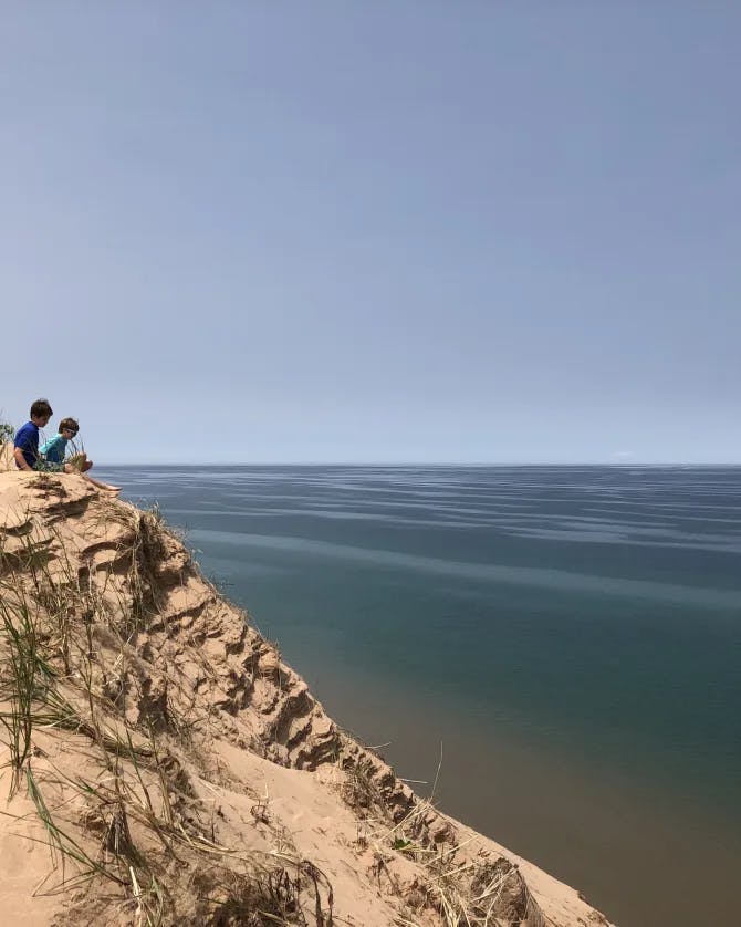 A picture of kids sitting on a cliff with a view of the sea
