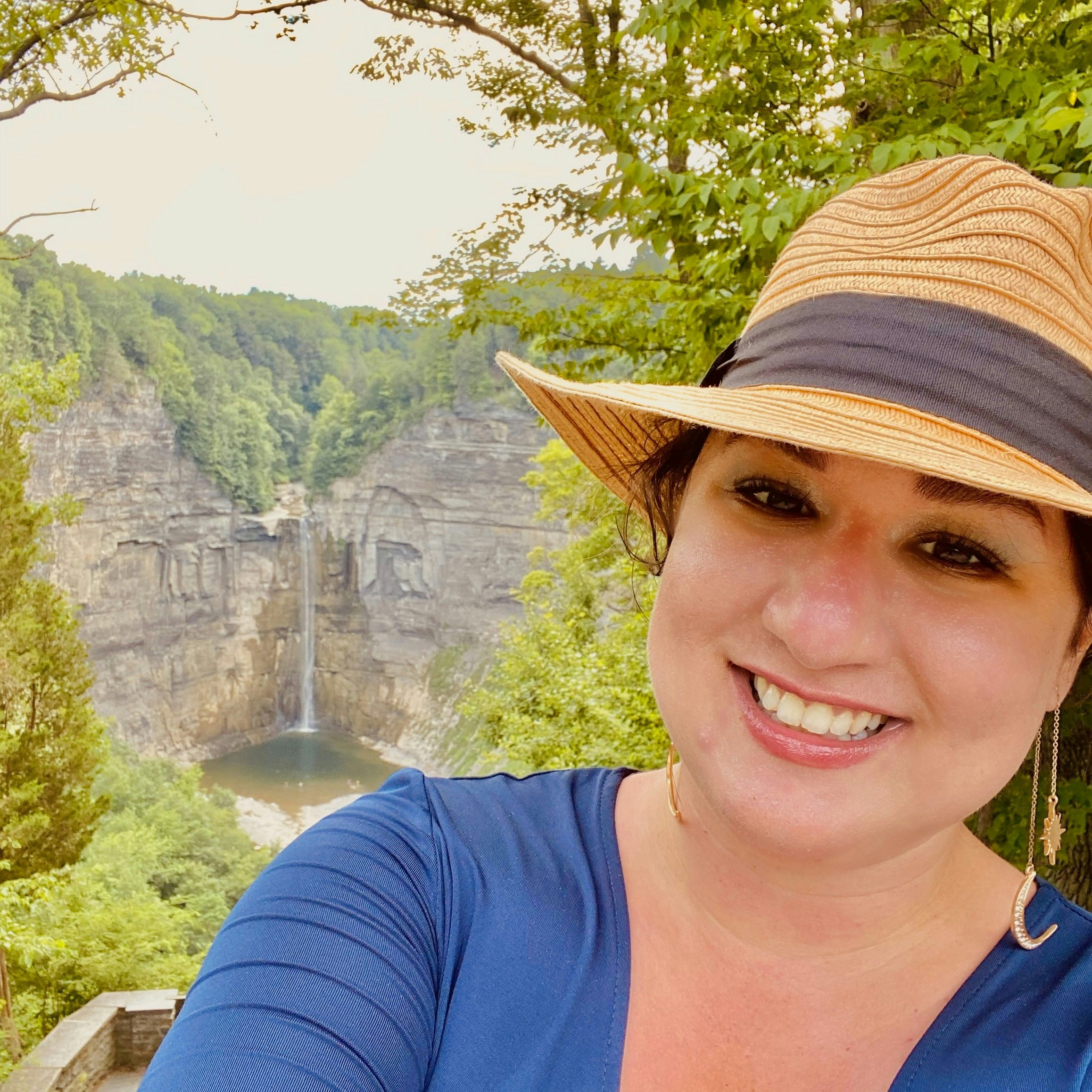 Travel advisor Elaine Zedack smiles in front of a picturesque waterfall.