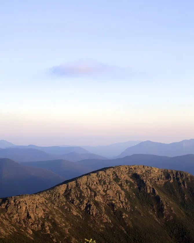 A peak view of Mount Bond at sunrise with a mountain range in the distance