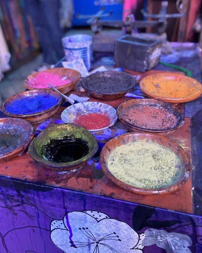 A picture of nine bowls of wool powder paint on a table in a craft room