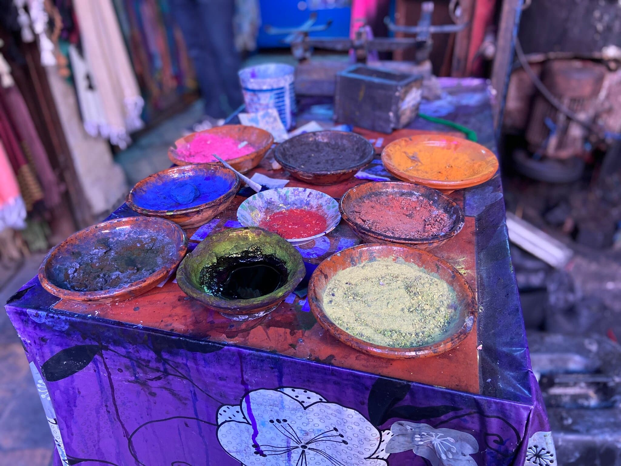 A picture of nine bowls of wool powder paint on a table in a craft room