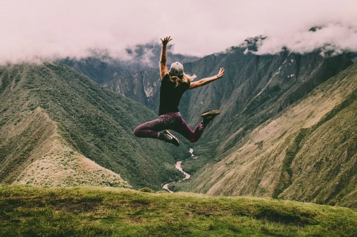 A young woman jumping in excitement somewhere along the verdant Inca Trail in Peru