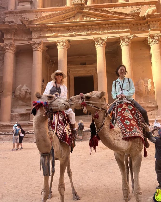 Susanne and a friend sitting on a camel in front of an ancient temple