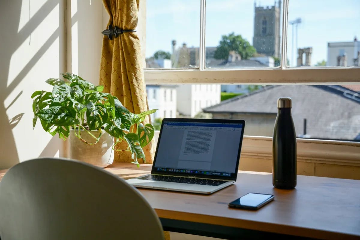 A laptop with a word program open and historic buildings faintly visible through a nearby window, indicating remote work from a nice hotel