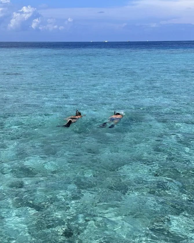 Two people floating in the turquoise blue water.