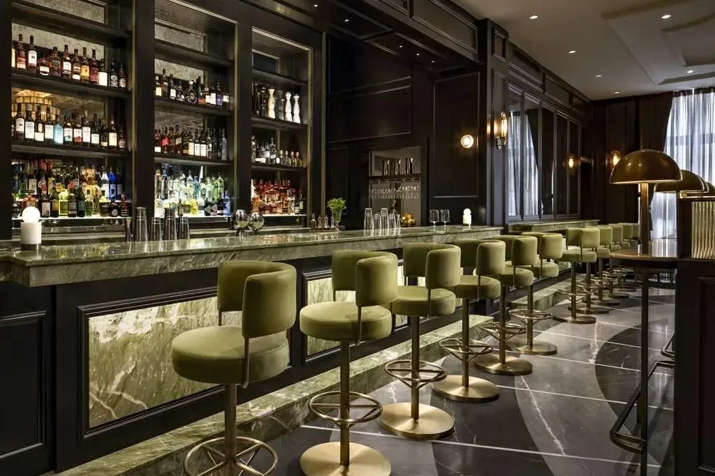 a dark and moody bar lined with green stools