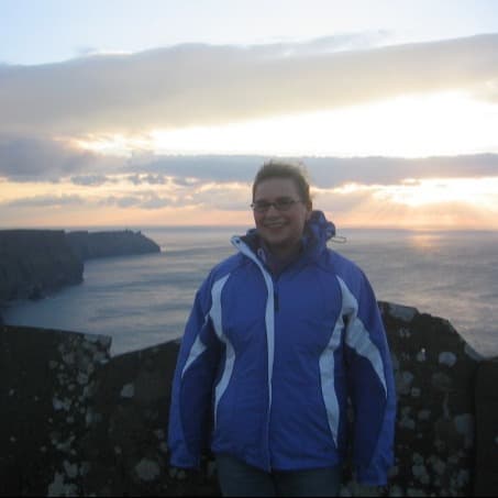 Travel Advisor in blue jacket in front of ocean.