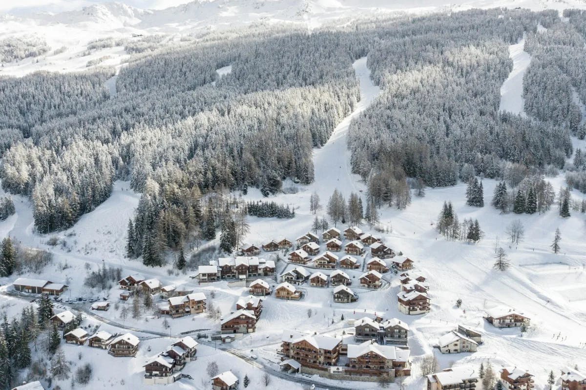 Snow blankets a small, ritzy ski resort in the French Alps. In the distance, vast forests are bisected by ski slopes
