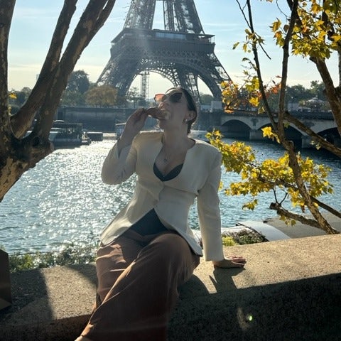 Travel advisor Shayna Steelman bites a pastry in front of the Eiffel Tower. 