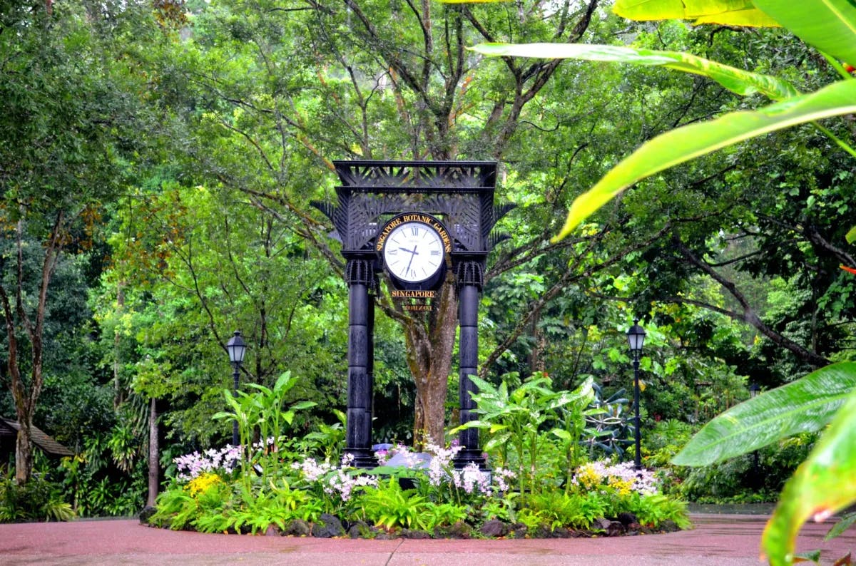 Clock in a lush garden with a circular pathway.