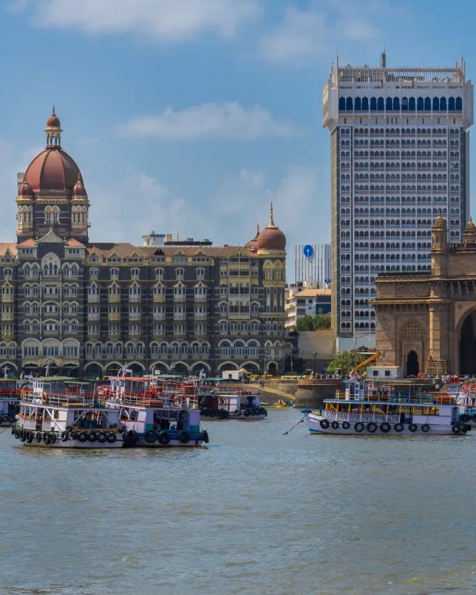 A picture of Gateway Of India Mumbai with water, boats and buildings