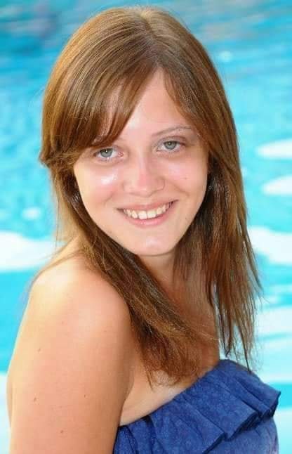 travel advisor Naomi Mckenna smiles by a pool wearing a dark blue dress