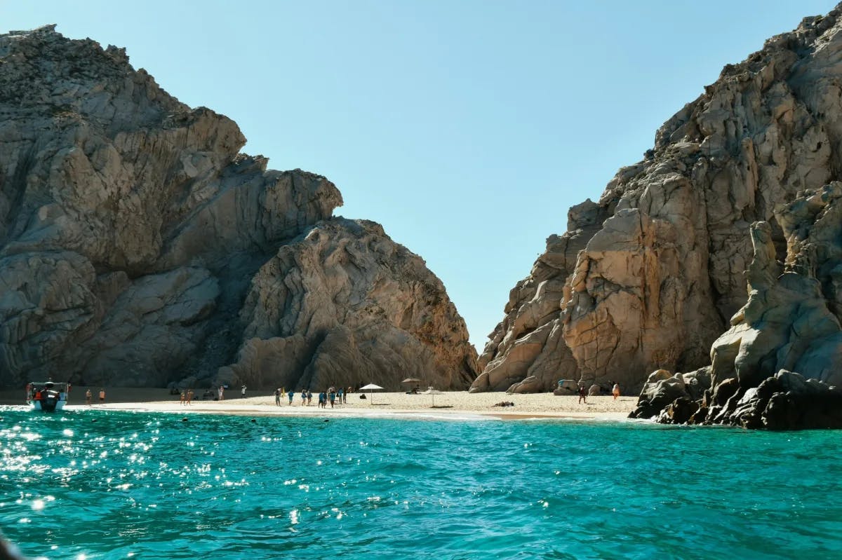 Beach with rocky hills and blue water. 