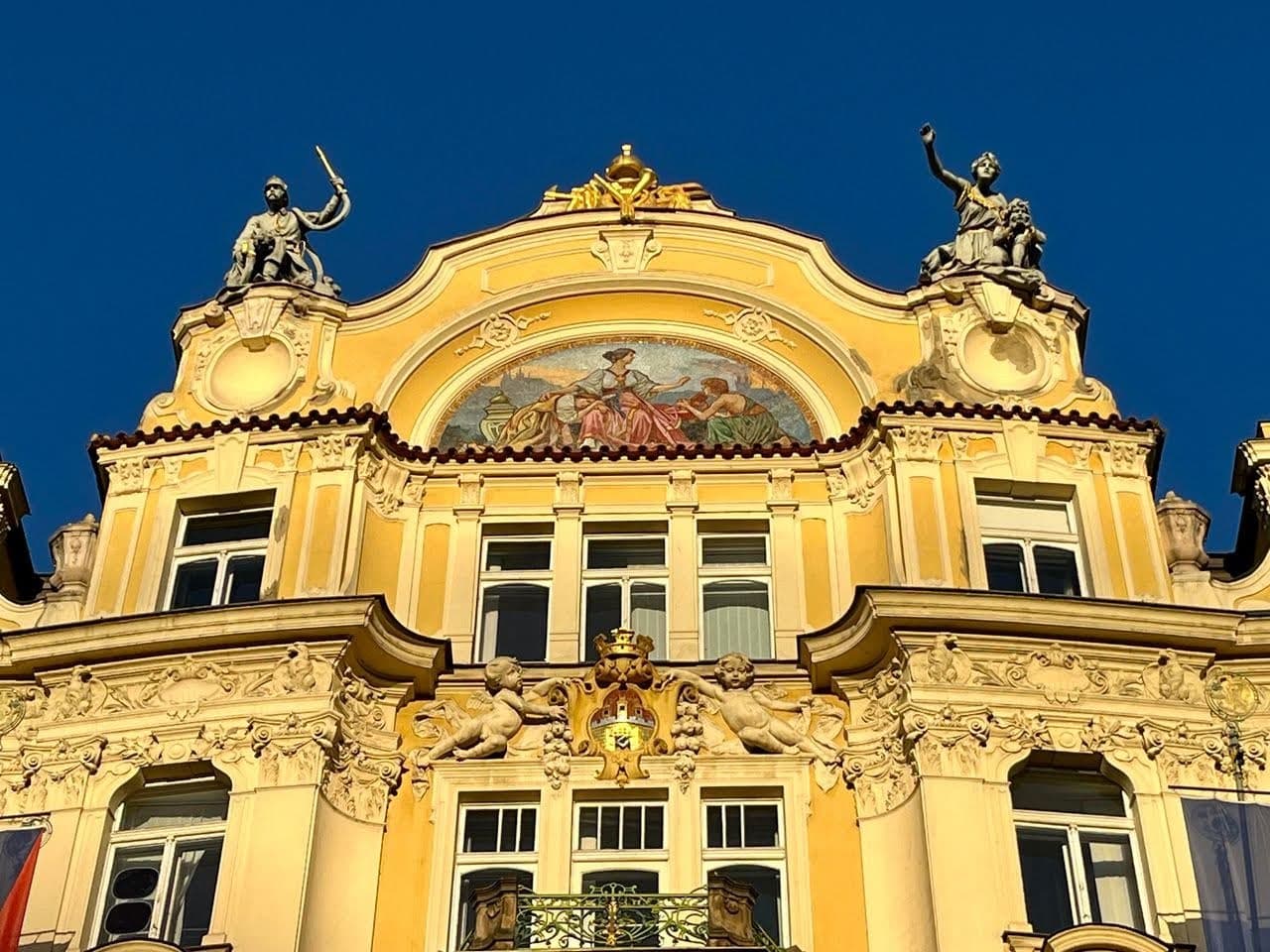 A yellow building with art designs in Prague with a blue sky background