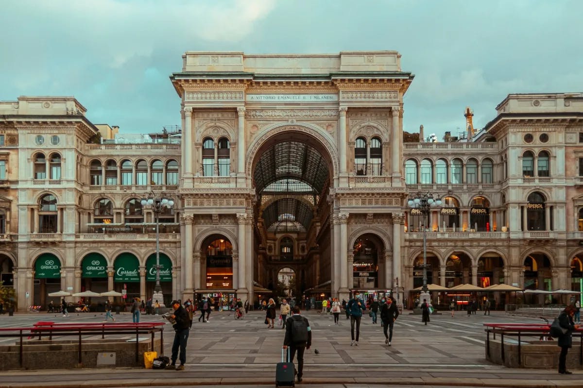Dozens of locals and travelers walk before the historic Galleria Vittorio Emanuelle II in Milan, Italy