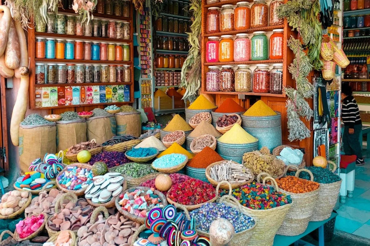 A vibrant assortment of spice- and candy-filled baskets, jars and hanging herbs at a vendor in the Marrakech Medina