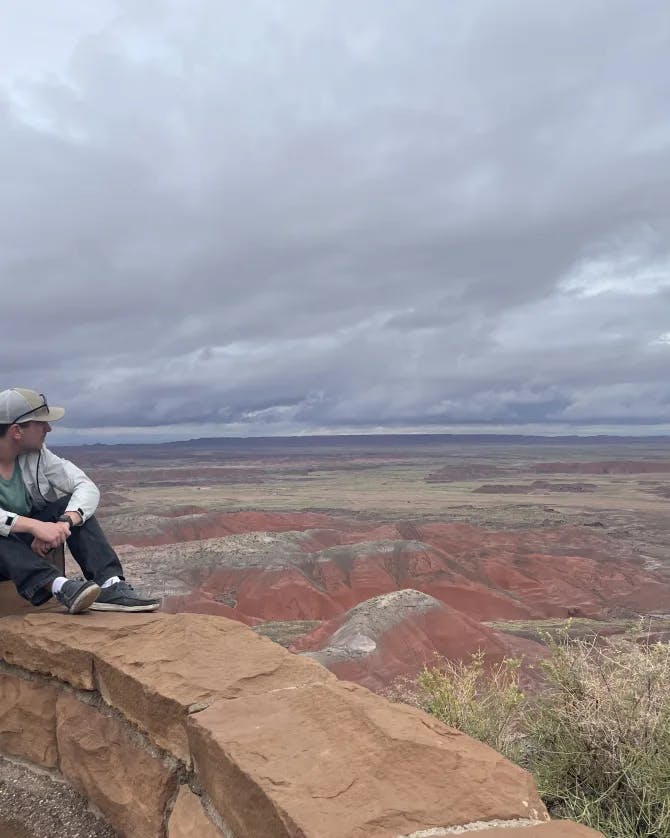 Sitting on a stone ledge overlooking rocky canyons on a cloudy day