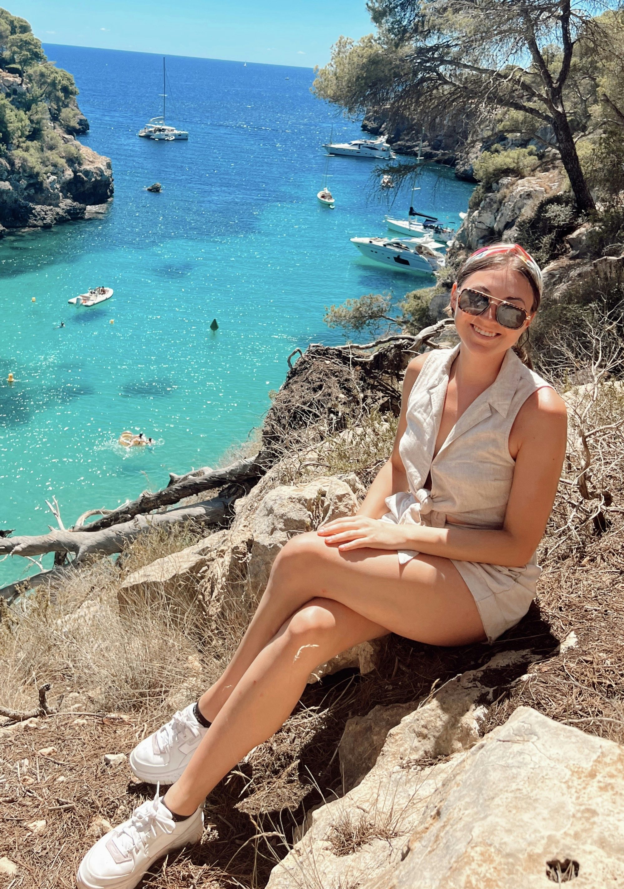 travel advisor Abby Kulwicki in sunglasses smiling on a trail overlooking a turquoise ocean lagoon