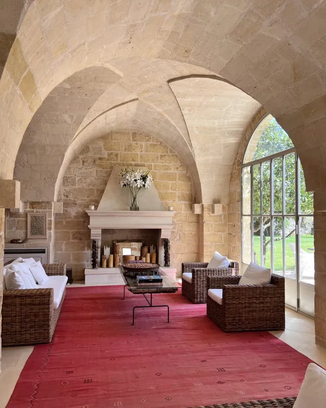 Picture of a sitting area with a red carpet and tan arched ceilings with a fireplace and large window