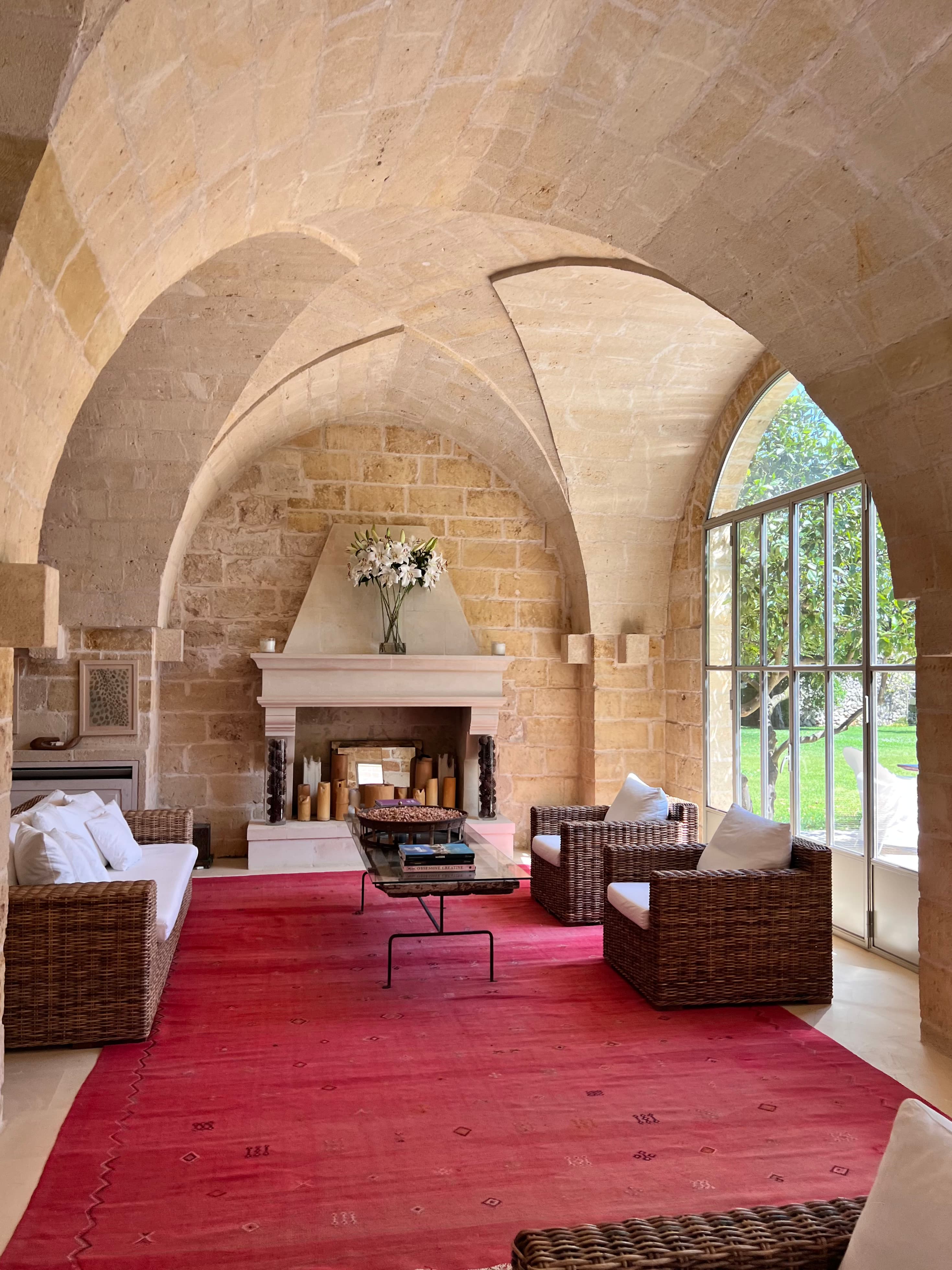 Picture of a sitting area with a red carpet and tan arched ceilings with a fireplace and large window