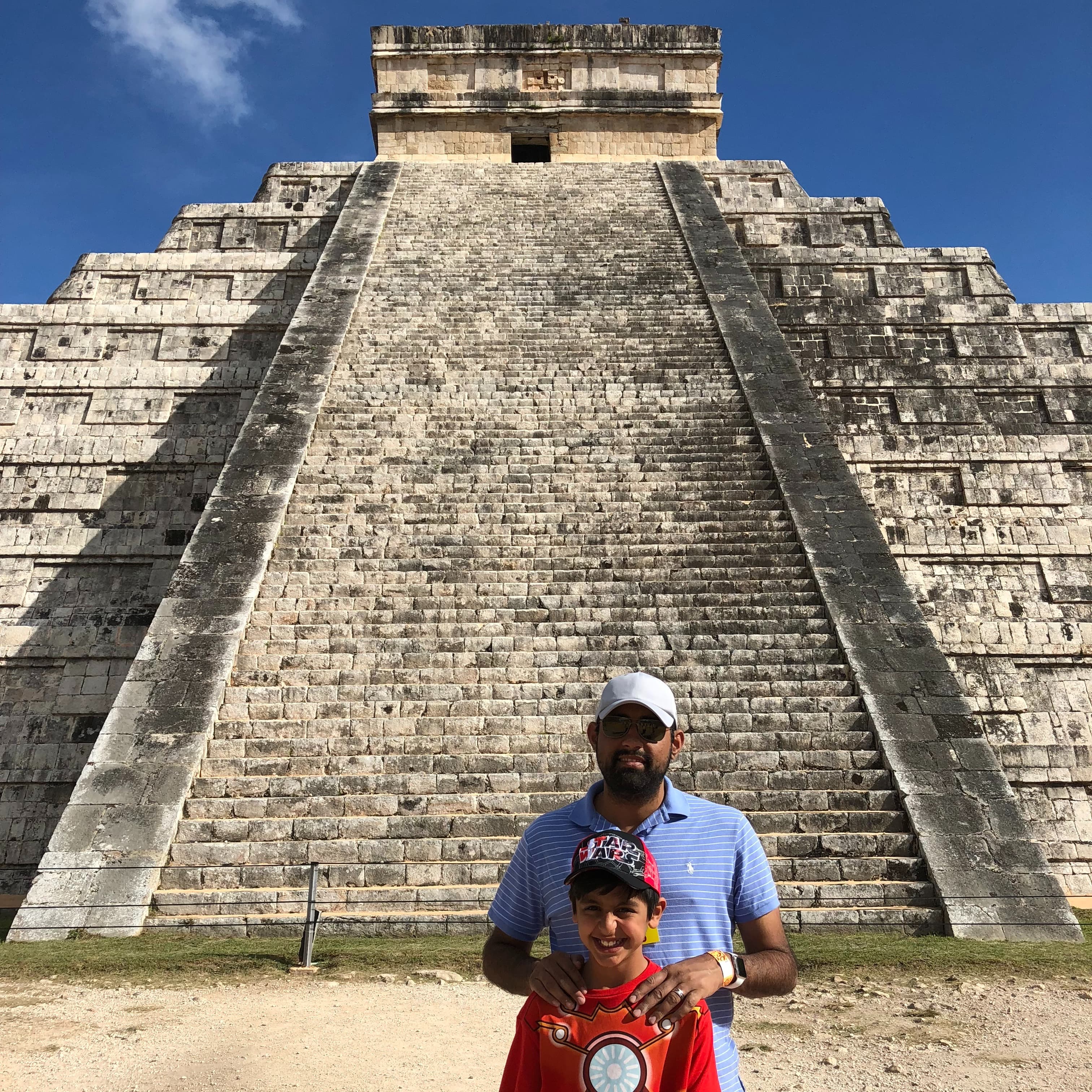 A man and a child posing in front of a pyramid.