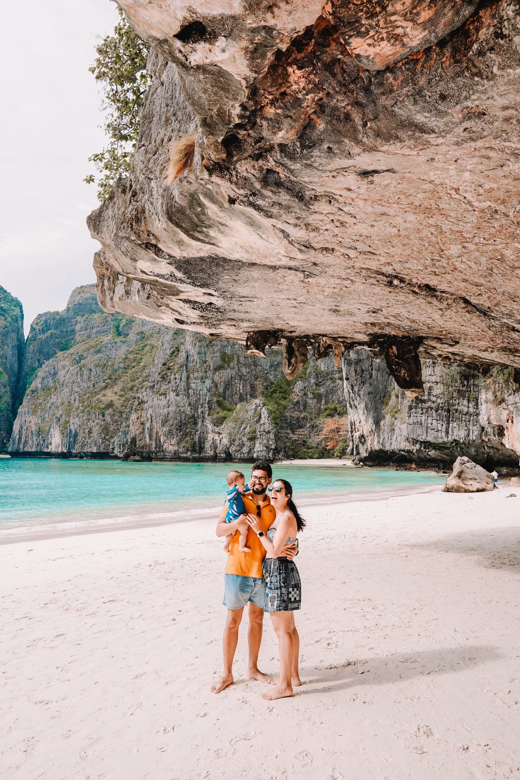 Maria with her husband and baby on a beach surrounded by stone mountains.